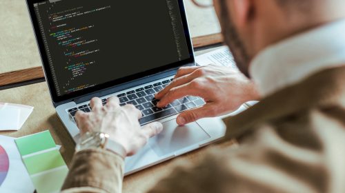 Cropped view of developer using laptop at table