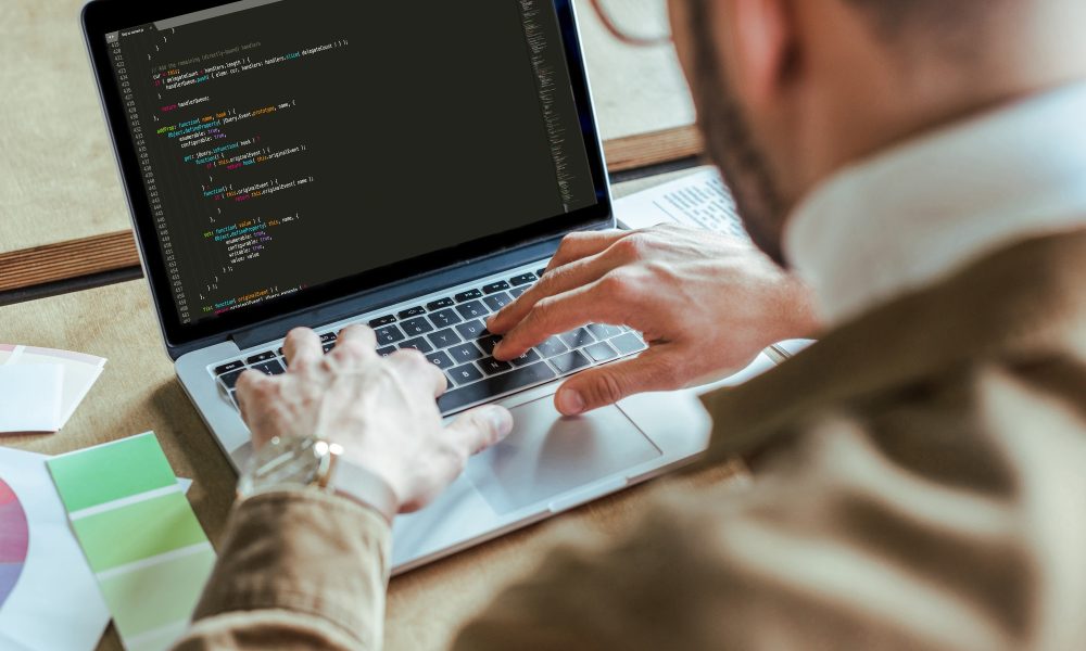 Cropped view of developer using laptop at table