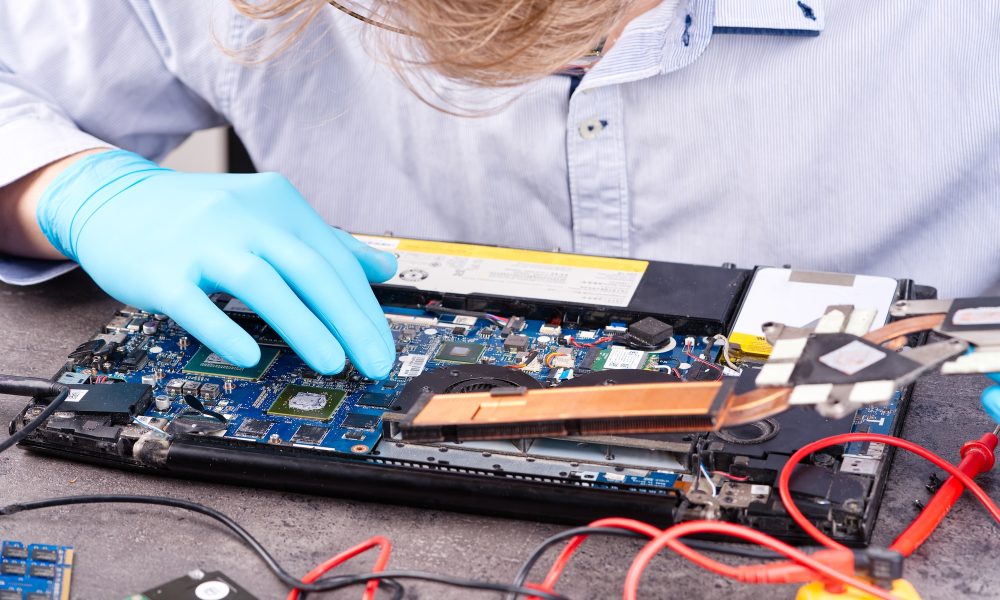 Hands of a technician repairing a broken laptop computer