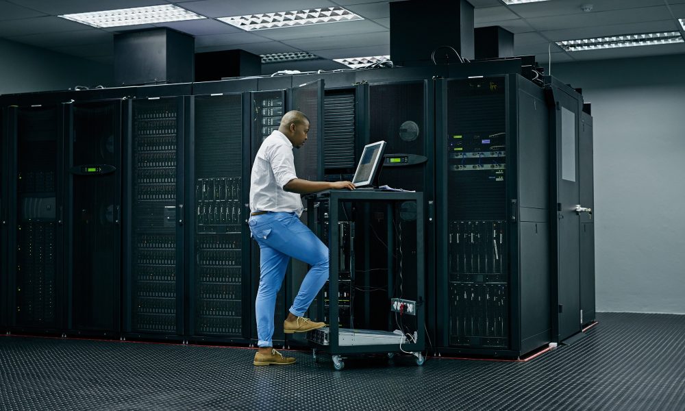 Skilled in all things IT. Shot of an IT technician using a computer while working in a data center.